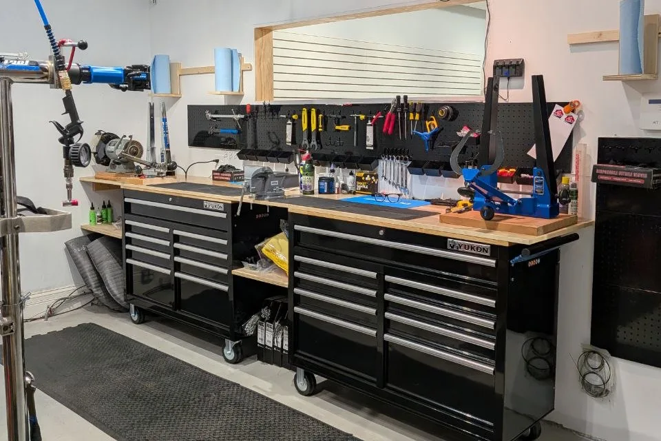 Chain Reaction's service bench with work stands, wall-mounted tools, and rolling tool chests